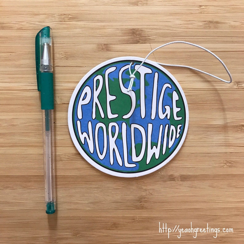 May include: A round, white car air freshener with a blue and green globe design. The text "PRESTIGE WORLDWIDE" is written in white on the globe.