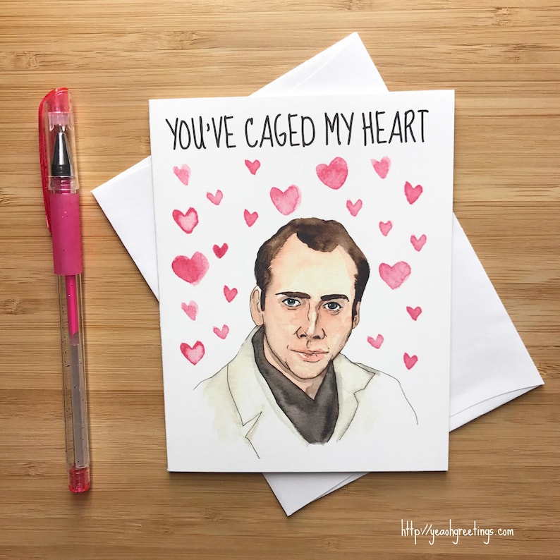 May include: A greeting card with a watercolor illustration of Nicolas Cage with the text "You've caged my heart" and pink hearts surrounding him.