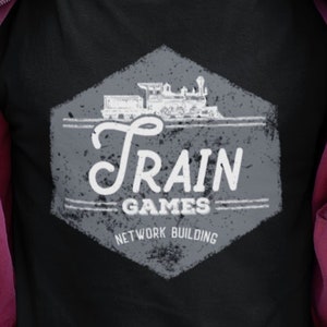 May include: A black t-shirt with a white graphic of a train and the text "Train Games Network Building".