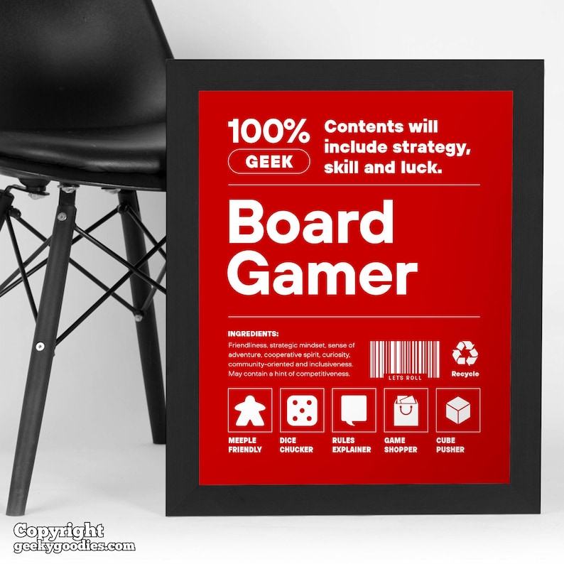 Pu&ograve; includere: Una stampa incorniciata con sfondo rosso e testo bianco che recita "Board Gamer". La stampa include il testo "100% GEEK" e "Contents will include strategy, skill and luck". Sotto ci sono icone e testo come "Meeple Friendly" e "Dice Chucker".