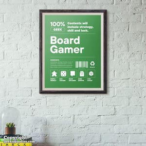 Pu&ograve; includere: Un poster verde incorniciato con le parole "Board Gamer" in grandi lettere bianche. Il poster include testo su strategia, abilit&agrave; e fortuna, insieme a icone per i componenti del gioco. La cornice &egrave; marrone scuro e lo sfondo &egrave; un muro di mattoni bianchi.