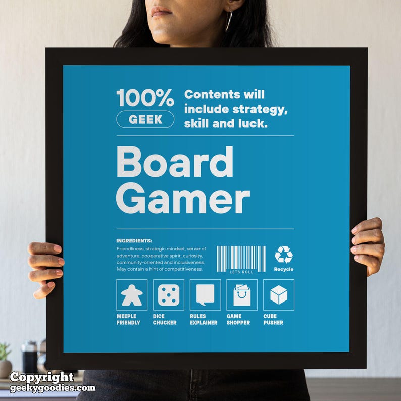 Pu&ograve; includere: Un poster incorniciato con sfondo blu e testo bianco che recita "Board Gamer". Il poster include il testo "100% GEEK" e "I contenuti includeranno strategia, abilit&agrave; e fortuna". Elenca anche "ingredienti" e icone.