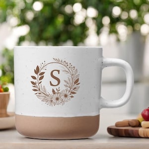 Taza personalizada con letra en zarcillo floral. Tu letra deseada grabada en una taza de cerámica blanca con 360ml