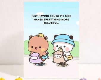 May include: A greeting card with a light blue sky background and the text "JUST HAVING YOU BY MY SIDE MAKES EVERYTHING MORE BEAUTIFUL." Two cartoon characters are featured, a brown bear and a panda, each with a hat and holding a toy.