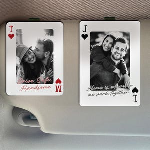 May include: Two playing card-shaped car visor clips with black and white photos of couples. One card reads "Drive Safe, Handsome" and the other reads "Home is wherever we park together."