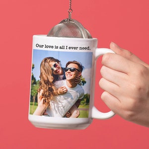 May include: White ceramic mug with a photo of a couple wearing sunglasses and the text "Our love is all I ever need."