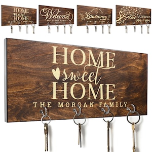 May include: A wooden key holder with the text "HOME sweet HOME THE MORGAN FAMILY" in gold lettering. The key holder has five hooks for hanging keys.