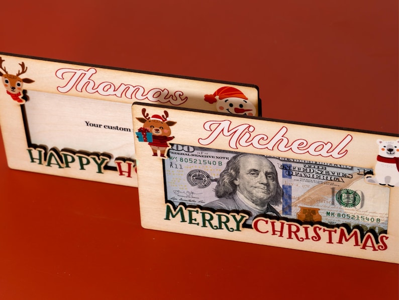 May include: Two wooden picture frames with Christmas themes. The top frame says "Thomas" and "Happy Holidays". The bottom frame says "Micheal" and "Merry Christmas".