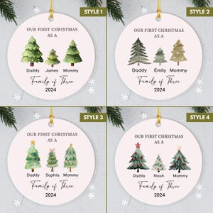 May include: Four different styles of personalized Christmas ornaments featuring a family of three with a watercolor-style illustration of three Christmas trees. The text reads "Our First Christmas as a Family of Three" with the year 2024.