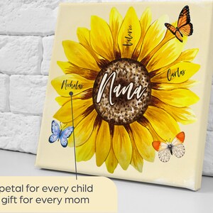May include: A canvas print featuring a large yellow sunflower with the word "Nana" in the center. The sunflower has the names "Nicholas", "Valerie", and "Carlos" on the petals. Butterflies are also featured. The text reads: "A petal for every child, a gift for every mom."