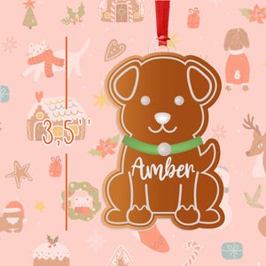 May include: A gingerbread dog ornament with a green collar and the name "Amber" written in white. The ornament is 3.5 inches tall and is perfect for hanging on a Christmas tree.