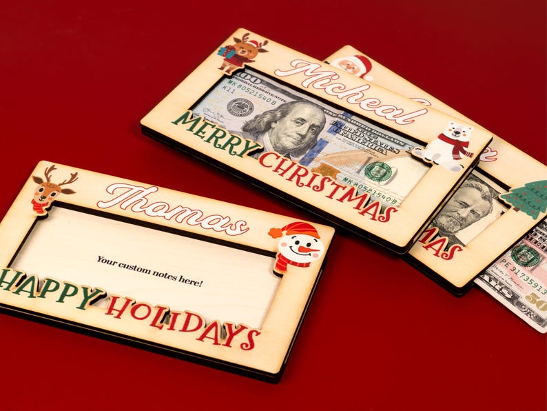May include: Three wooden picture frames with a Christmas theme. Each frame has a different holiday character and the words "Merry Christmas" or "Happy Holidays". The frames are designed to hold cash or gift cards.
