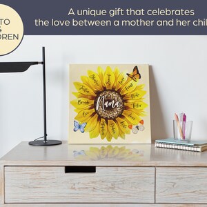 May include: A personalized sunflower canvas print with the word "Nana" in the center, surrounded by names. The print features a yellow sunflower design with butterflies. Text on the print reads "A unique gift that celebrates the love between a mother and her children."