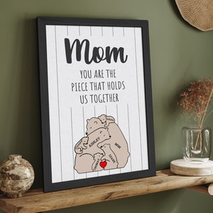 May include: A black framed print with the text "Mom you are the piece that holds us together" and a graphic of a family of bears hugging each other. The bears are labeled with names like "Mom", "Ashley", "Thomas", "Ethan", and "Sarah".