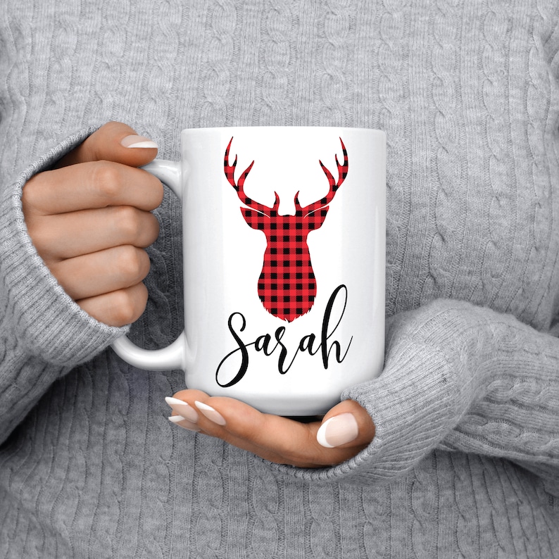 Puede incluir: Taza de cer&aacute;mica blanca con un dise&ntilde;o de cabeza de ciervo de cuadros rojos y negros y el nombre "Sarah" escrito en cursiva negra.