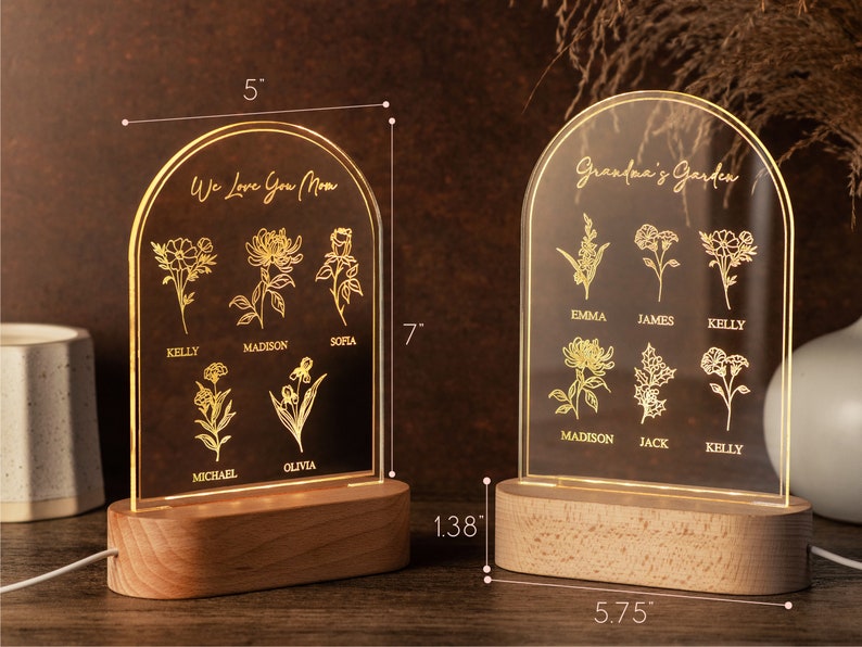 May include: Two illuminated acrylic signs with wooden bases. One reads "We Love You Mom" with floral designs and names. The other says "Grandma's Garden" with floral designs and names. Each sign is 7 inches tall and 5 inches wide.
