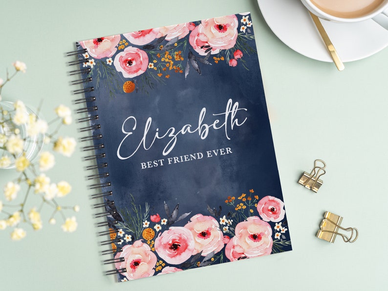 May include: A blue spiral bound notebook with a floral design and the text "Elizabeth Best Friend Ever" on the cover.