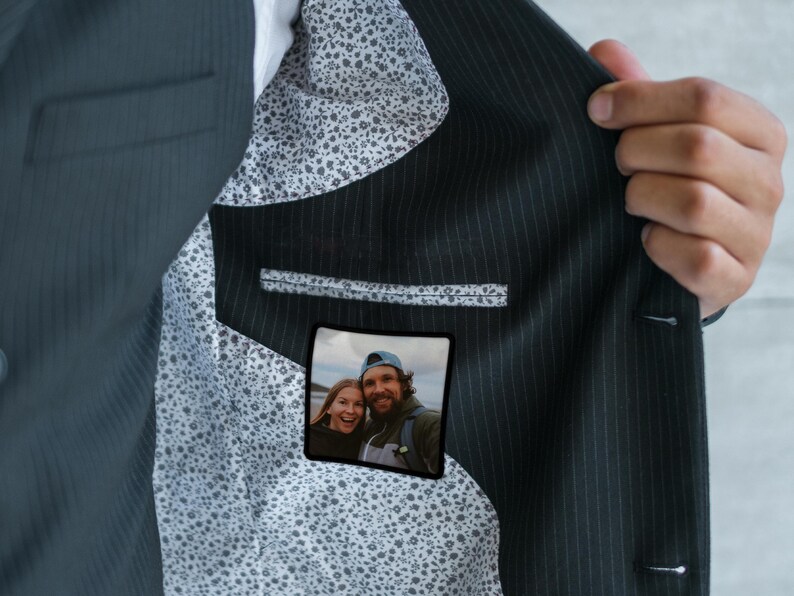 May include: A dark blue suit jacket with a white and black patterned lining. A small photo of a couple is visible in the pocket.