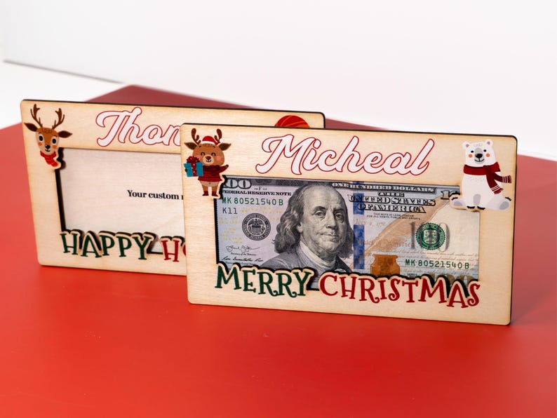 May include: Two wooden picture frames with a Christmas theme. The top frame says "Thon" and the bottom frame says "Micheal" with a dollar bill and a polar bear illustration. Both frames say "Happy Holidays" and "Merry Christmas".