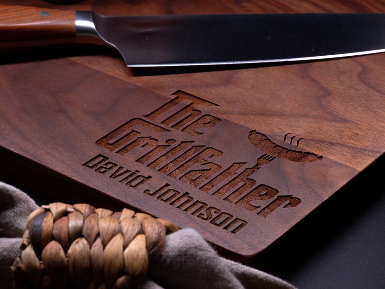 May include: A personalized walnut cutting board with the text "The Grillfather David Johnson" and a stylized image of a hot dog and fork.