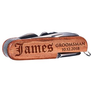 Może przedstawiać: Drewniany scyzoryk z grawerowanym napisem "James GROOMSMAN 10.12.2018".