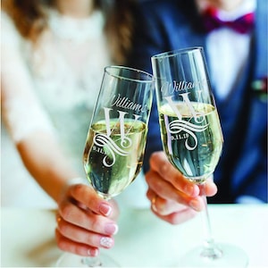 May include: Two champagne flutes with the text "Williams" and the date "9.11.19" etched on them. The flutes are filled with champagne and are being held by a couple.