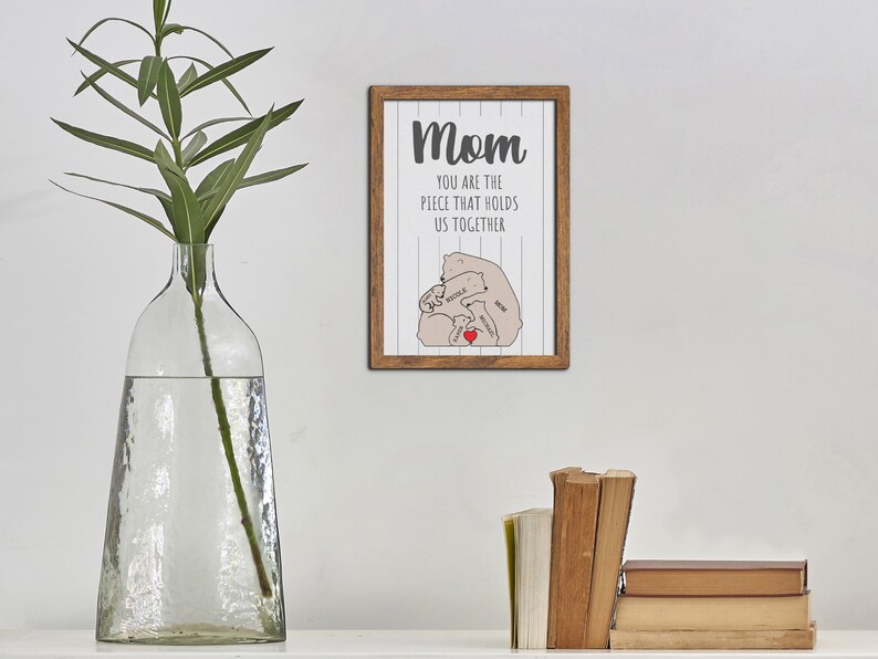 May include: A framed print with a white background and gray text that reads "Mom you are the piece that holds us together". The print features a stylized illustration of a mother bear and three cubs.