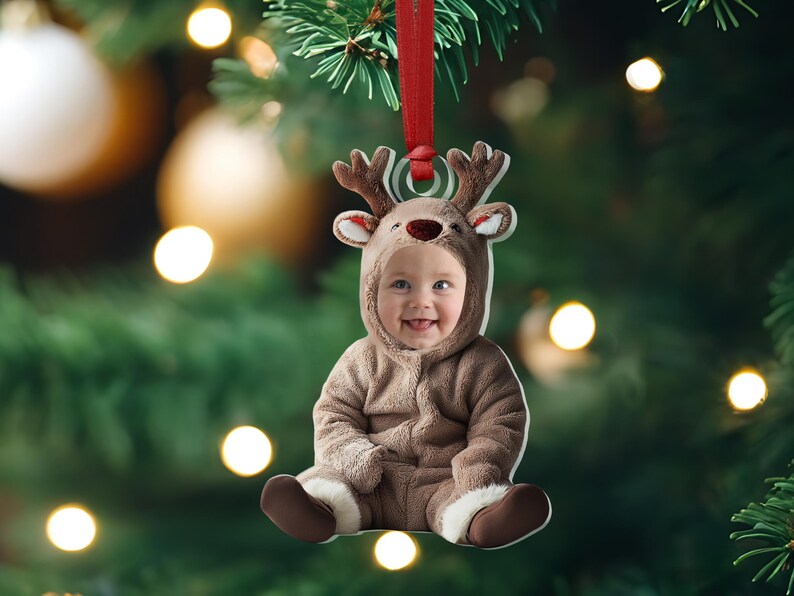 Pu&ograve; includere: Un ornamento natalizio con un bambino vestito con un costume da renna marrone. L'ornamento &egrave; in metallo e ha un nastro rosso attaccato alla parte superiore.