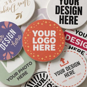May include: A collection of round ceramic coasters featuring various custom designs, including text such as YOUR DESIGN HERE, YOUR LOGO HERE, and YOUR PHOTO HERE, displayed in colors like orange, purple, green, white, and black with graphic patterns.