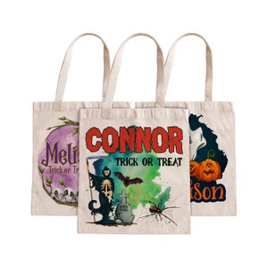 May include: Three white canvas tote bags with Halloween designs. The first bag has a purple and pink design with the text "Mel Trick or Treat". The second bag has a green and blue design with the text "Connor Trick or Treat". The third bag has a black and blue design with the text "Tyson Trick or Treat".