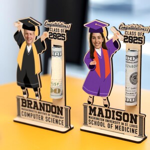 Op de afbeelding: Houten afstudeercadeau met twee figuren in afstudeerkleding, met diploma's. Elk figuur heeft een gleuf voor opgerolde bankbiljetten. De bases lezen "BRANDON COMPUTER SCIENCE" en "MADISON SCHOOL OF MEDICINE" met "CLASS OF 2025" erboven.