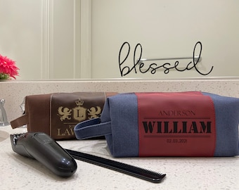 May include: Two toiletry bags, one brown with gold accents and the other blue with a red leather panel. The blue bag has the name "William Anderson" and the date "02.03.2021" printed on it.