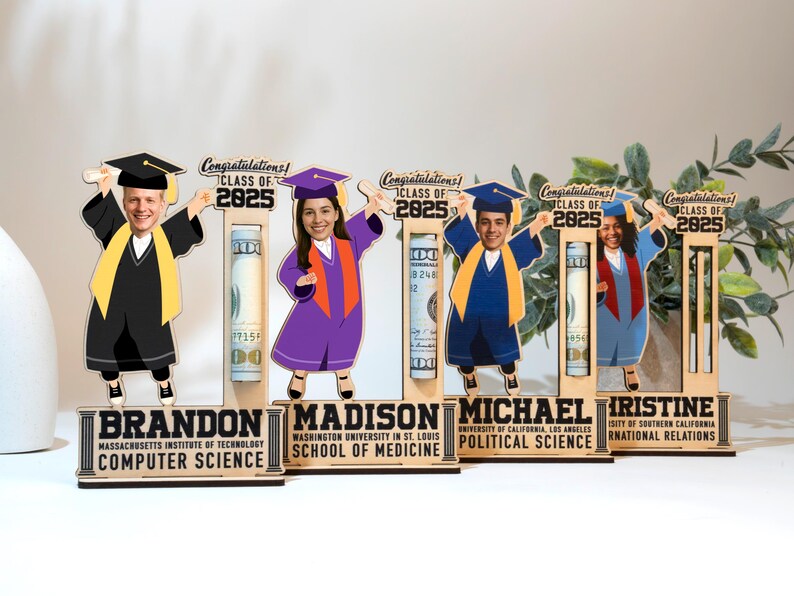 Op de afbeelding: Houten displays met een afstudeerthema met stripfiguren in afstudeerkleding, elk met een diploma. De displays bevatten de tekst "Gefeliciteerd! Klas van 2025" en gepersonaliseerde namen en diploma's. Elke display bevat een opgerolde bankbiljet.