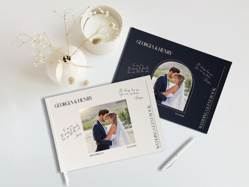 Puede incluir: Dos libros de invitados de boda blancos con una cubierta azul marino. Las cubiertas presentan una foto de la pareja y el texto "Georgia & Henry" y "Libro de invitados de la boda".