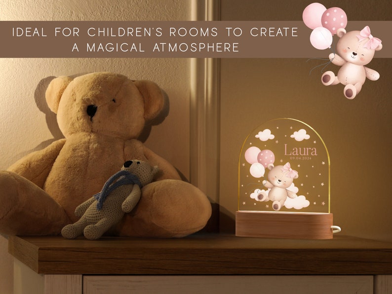 May include: A personalized night light with a teddy bear design, balloons, and the name "Laura" and date. The light sits on a wooden base. A large teddy bear and a smaller stuffed bear are also in the image.