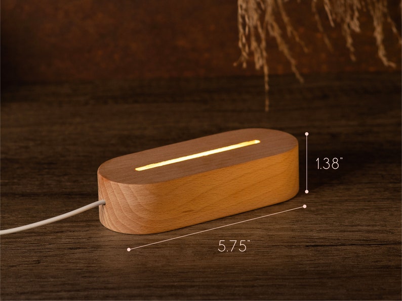 May include: A wooden LED light base, measuring 5.75 inches long and 1.38 inches high, with a warm, glowing light. The light is rectangular with rounded edges and a white power cord.