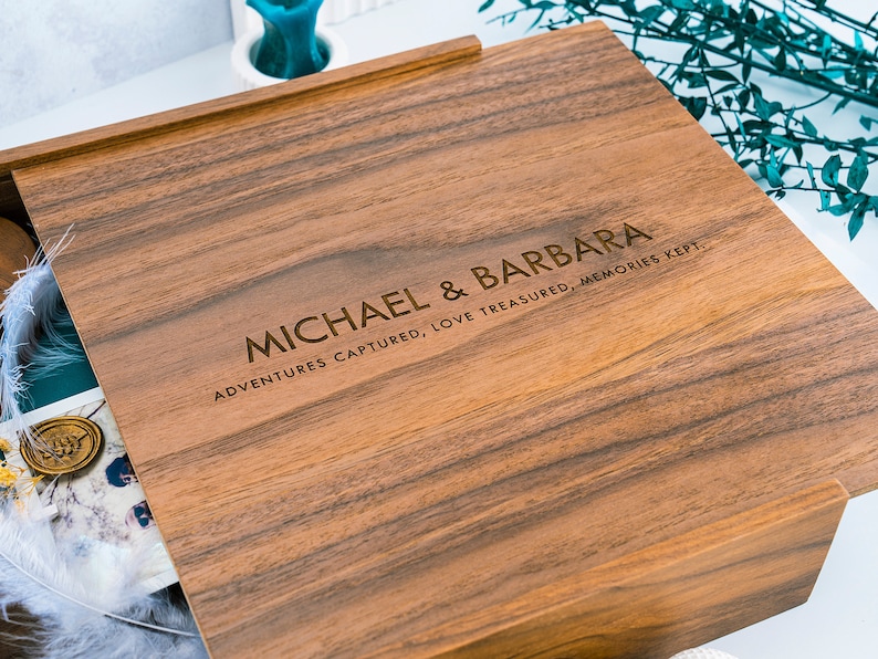 May include: A wooden box with a hinged lid. The lid is engraved with the text "MICHAEL & BARBARA ADVENTURES CAPTURED, LOVE TREASURED, MEMORIES KEPT."