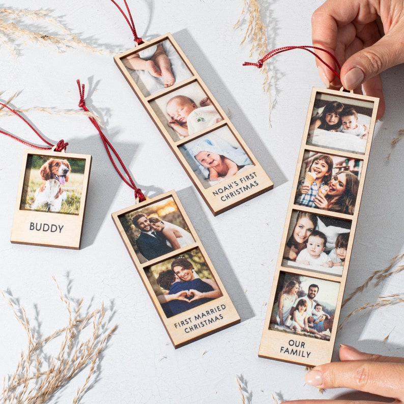 May include: Set of five wooden Christmas ornaments with photos and text. The ornaments feature a dog, a family, a couple, a baby, and a family with a child. The text on the ornaments reads "Buddy", "Our Family", "First Married Christmas", "Noah's First Christmas", and "Buddy".