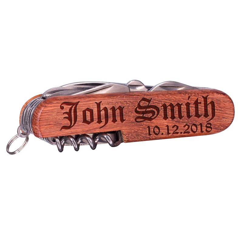 Może przedstawiać: Wielofunkcyjne narzędzie z brązowym drewnianym uchwytem, srebrnym ostrzem i spersonalizowanym napisem "John Smith 10.12.2018".
