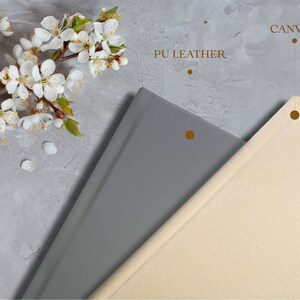 Puede incluir: Dos cubiertas de &aacute;lbum de fotos, una gris y otra beige, con las palabras "PU Leather" y "Canvas" impresas encima.