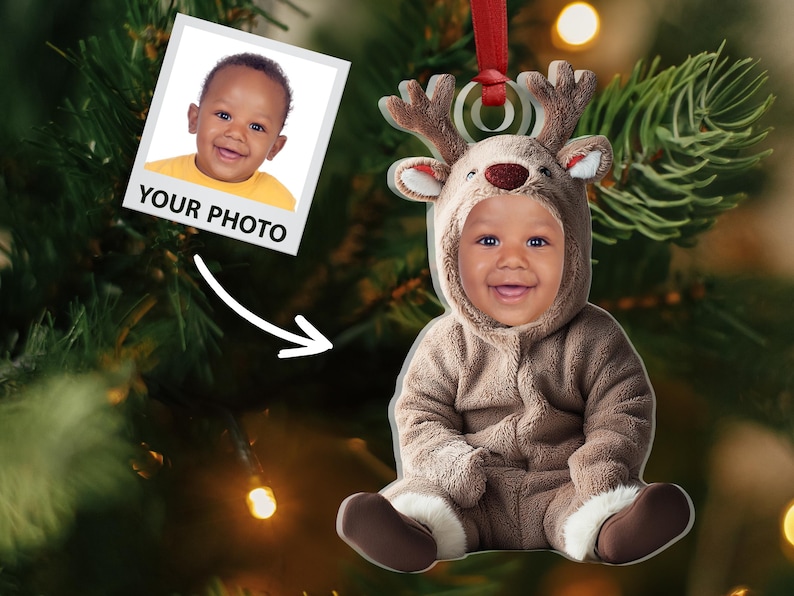 Pu&ograve; includere: Un ornamento natalizio personalizzato con un bambino vestito da renna. L'ornamento &egrave; realizzato in acrilico trasparente e ha un nastro rosso per appenderlo. Il viso del bambino &egrave; visibile attraverso l'ornamento, e il testo "YOUR PHOTO" &egrave; stampato sull'ornamento.