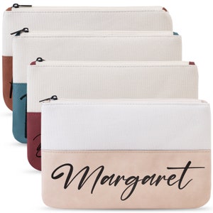 K&ouml;nnte beinhalten: Set aus drei wei&szlig;en Canvas-Rei&szlig;verschlusstaschen mit braunem, blaugr&uuml;nem und rosafarbenem Boden. Der Boden der Tasche tr&auml;gt den Namen "Margaret" in schwarzer Kursivschrift.