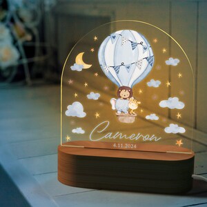May include: A decorative night light featuring a watercolor illustration of a hot air balloon with a lion and giraffe. The light has a wooden base and the name "Cameron" and date "4.11.2024" are displayed.