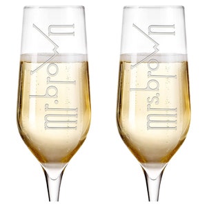 May include: Two champagne flutes with the words "Mr. & Mrs." etched on them. The flutes are filled with champagne.