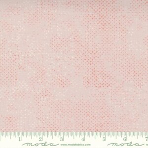 Peut inclure: Tissu rose clair avec un motif à pois dans les tons de rose et de blanc. Le tissu a une texture subtile et une règle le long du bord inférieur. Le mot "moda" est imprimé sur la règle.