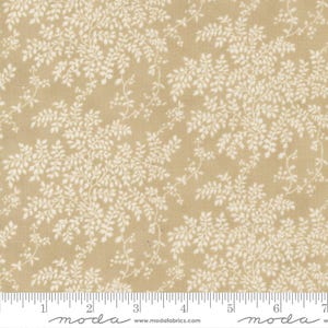 May include: A tan fabric featuring a repeating white botanical pattern of delicate leaves and thin stems. A white ruler is visible at the bottom edge, showing measurements in inches, with the text moda and www.modafabrics.com printed below.
