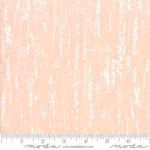 May include: Peach-colored fabric with a textured, vertical, white, brushstroke-like pattern. A ruler is at the bottom of the fabric, with the word "moda" and the website address www.modafabrics.com printed on it.