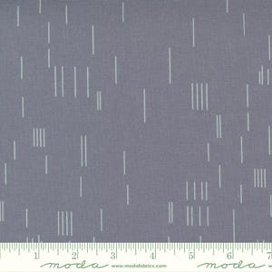 May include: A close-up of a fabric with a gray background and a pattern of vertical, light-colored lines. Some lines are single, while others are grouped in sets of three or four. A ruler is at the bottom, with the word "moda" and the website address.