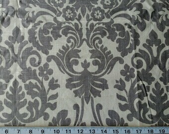 May include: A close-up of a beige fabric with a gray damask pattern. The fabric has a subtle texture and a repeating design of stylized flowers and leaves.