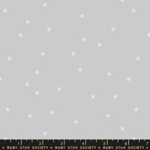 Puede incluir: Una tela gris claro con un patrón repetido de copos de nieve blancos. Una regla se encuentra en el borde inferior con el texto "RUBY STAR SOCIETY". Esta tela es adecuada para acolchar, coser y otros proyectos de manualidades.